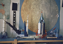 831238 Afbeelding van enkele schaalmodellen uit de ruimtevaart voor een wandkaart van de maan op de kamer van een ...